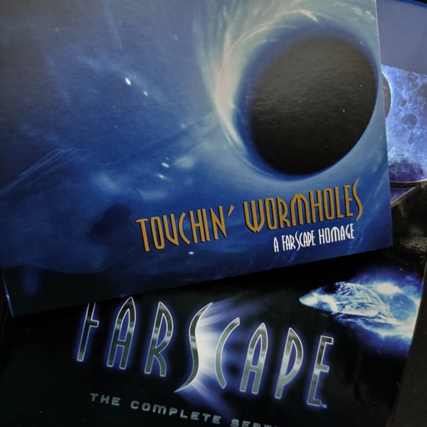 Copy of Touchin' Wormholes CD overlaying a Blu-ray case of the television show Farscape